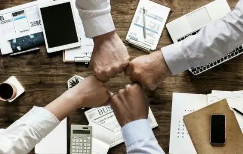 Misión: Unificar Fuerzas para el Éxito Personas chocando puños, unificando fuerzas en equipo, representación de la misión de la empresa